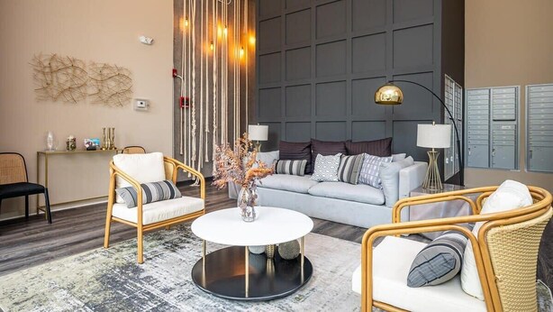A modern hotel lobby with a grey sofa, wicker chairs, a round coffee table, and a decorative wall with vertical lines and lights. - Cozy Modern Home in Downtown Atlanta (Atlanta)