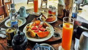 A wooden table with various breakfast items including fruit, tea, and juice. - B&B Ayla Beach House (Zanzibar Kiwengwa)