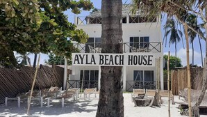 A sign for 'AYLA BEACH HOUSE' with a modern white building, palm trees, and beach chairs in the foreground. - B&B Ayla Beach House (Zanzibar Kiwengwa)