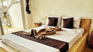 A bed with a white mattress and brown blanket, two pillows, and a wooden headboard. - B&B Ayla Beach House (Zanzibar Kiwengwa)