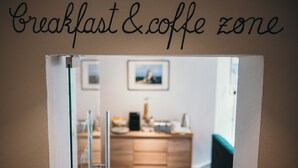 A breakfast and coffee zone with a wooden counter and a framed picture on the wall. - NEST Guesthouse (Drobeta-Turnu Severin)