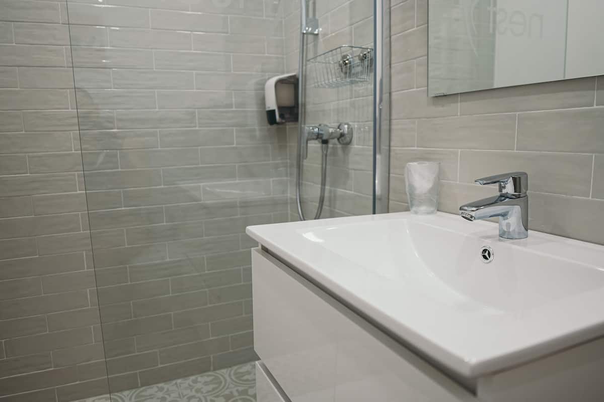Ein Badezimmer mit Waschbecken, einer Duschkabine aus Glas und einer Seifenspender.
