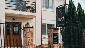 A two-story building with a sign reading "nest guesthouse" and a wooden door. - NEST Guesthouse (Drobeta-Turnu Severin)