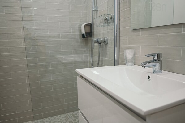 A bathroom with a white sink, a glass shower enclosure, and a tiled wall.
