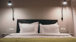 A hotel room with a bed, two bedside lamps, and a nightstand. - NEST Guesthouse (Drobeta-Turnu Severin)