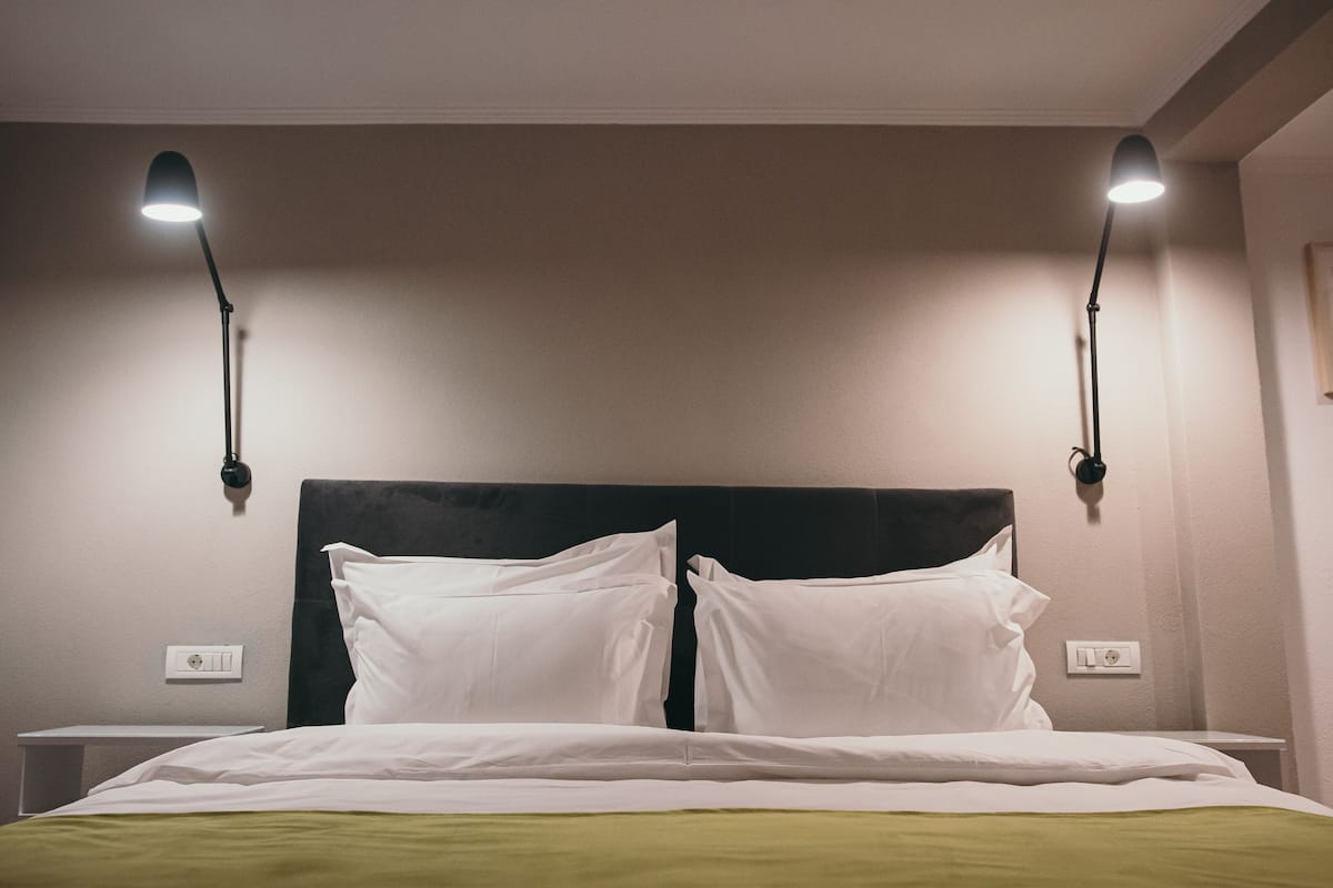 Ein Hotelzimmer mit einem Bett, zwei Nachttischlampen und einem Nachttisch.