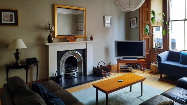 A living room with a fireplace, a television, and a sofa. - Cornwall Street [297] is a Spacious and charming apartment close to Usher Hall (Edinburgh)