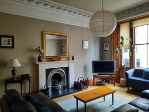 Een woonkamer met een open haard, een televisie en een bank.