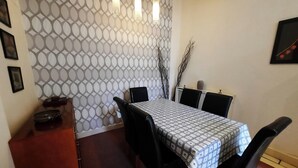 A dining area with a patterned wall, a table with a checkered tablecloth, black chairs, and a small cabinet. - Cornwall Street [297] is a Spacious and charming apartment close to Usher Hall (Edinburgh)