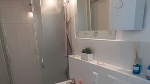 Un baño con ducha, lavabo, inodoro y espejo.