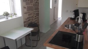 Una cocina compacta con una pared de acento de piedra, una mesa de comedor y un horno empotrado.
