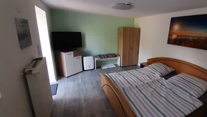 Un dormitorio con cama, televisor, armario y escritorio.