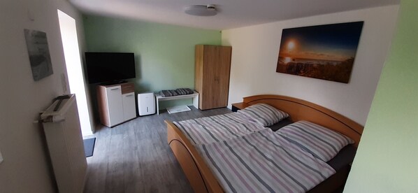 Ein Schlafzimmer mit Bett, Fernseher, Kleiderschrank und Schreibtisch.