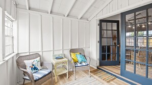 Een kamer met rieten stoelen, een tafeltje en een blauwe deur naar een andere ruimte.