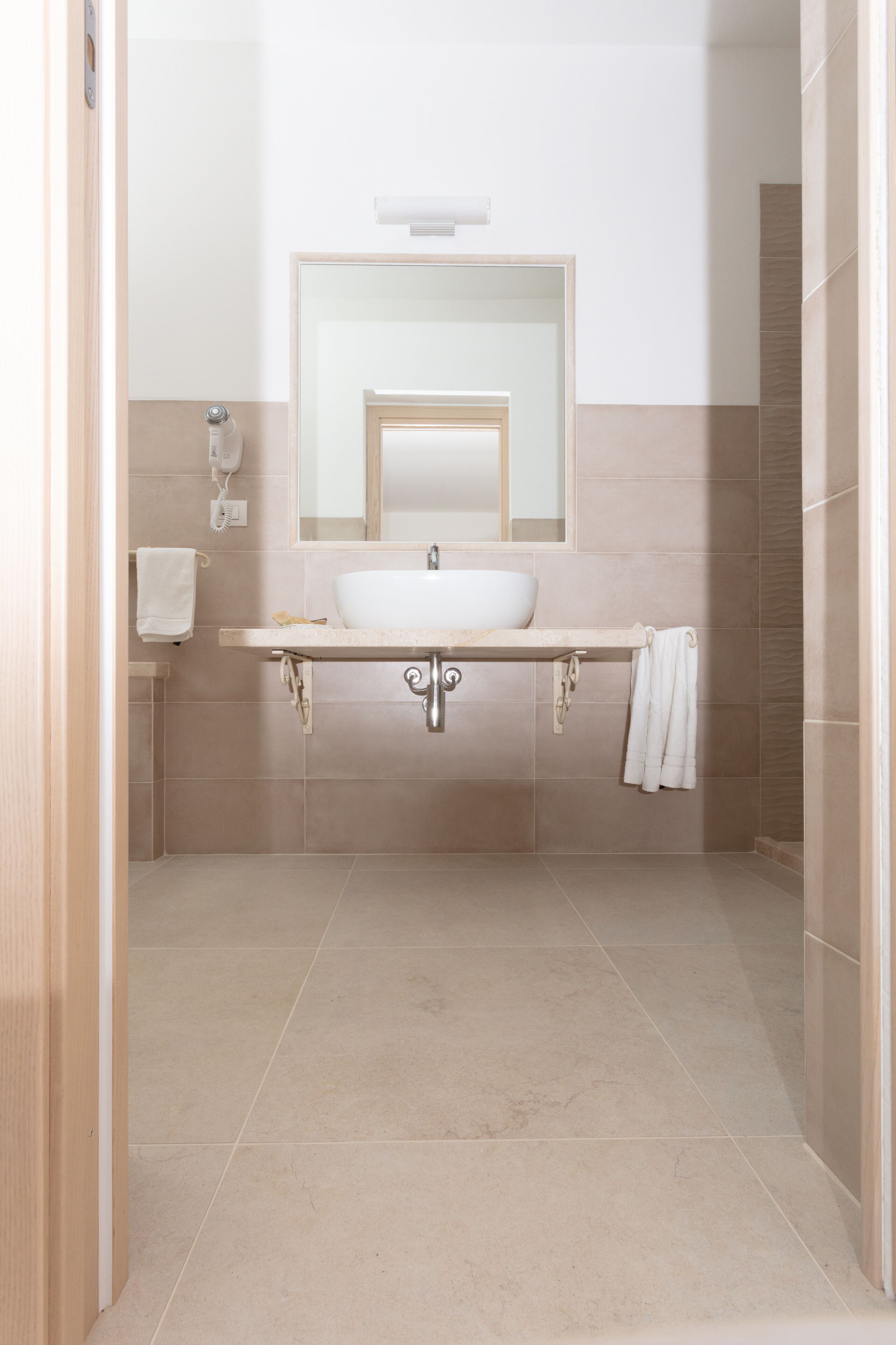 A bathroom with a sink, mirror, towel rack, and a hairdryer.