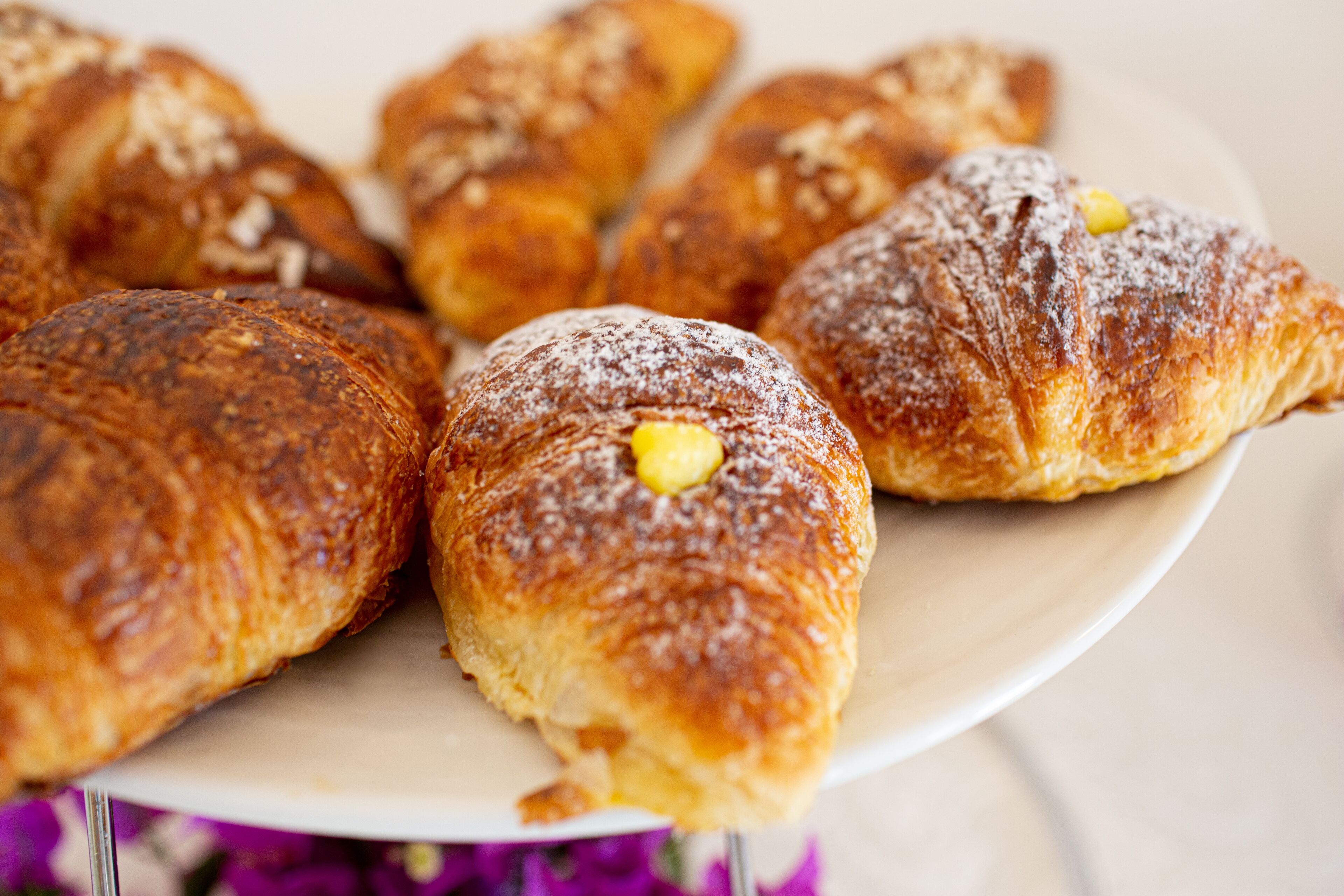 Un plato de pasteles, incluyendo croissants y un pastel con relleno amarillo.