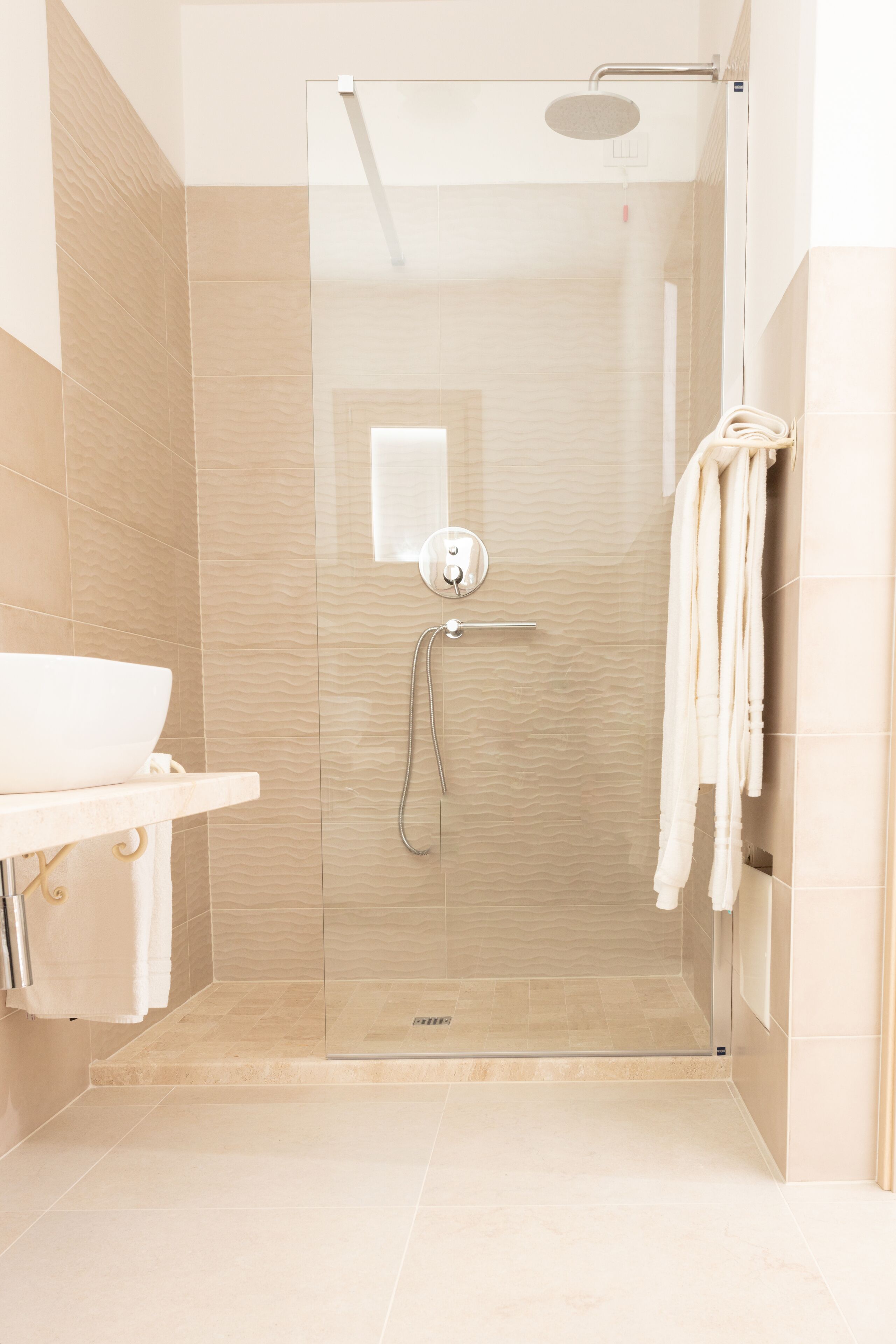 A modern bathroom with a glass-enclosed shower, a white sink, and a towel rack.