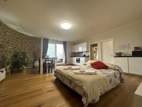 Quarto com cama, escrivaninha e cozinha compacta.