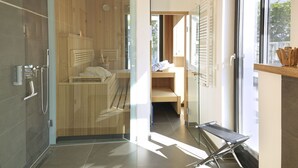 A modern spa room with a wooden sauna, a glass shower enclosure, and a bench. - Baltic Cloud, Villa Augustine (Binz)