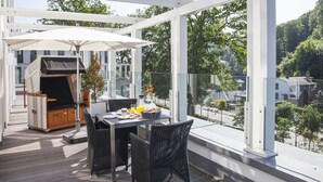 A covered outdoor dining area with a grill, wicker chairs, and a table set for breakfast. - Baltic Cloud, Villa Augustine (Binz)