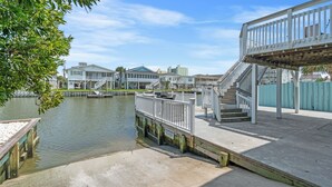 A waterfront property with a dock, a wooden deck, and a staircase leading to a covered area. - Driftwood Too - 4 Bed/2 Bath Home on the Channel in Cherry Grove (North Myrtle Beach)