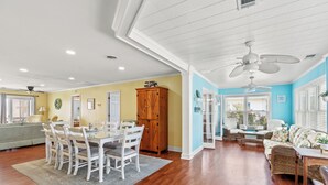 A spacious living area with a dining table, chairs, a sofa, and a ceiling fan. - Driftwood Too - 4 Bed/2 Bath Home on the Channel in Cherry Grove (North Myrtle Beach)