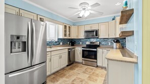 A modern kitchen with stainless steel appliances, light blue walls, and a tiled backsplash. - Driftwood Too - 4 Bed/2 Bath Home on the Channel in Cherry Grove (North Myrtle Beach)