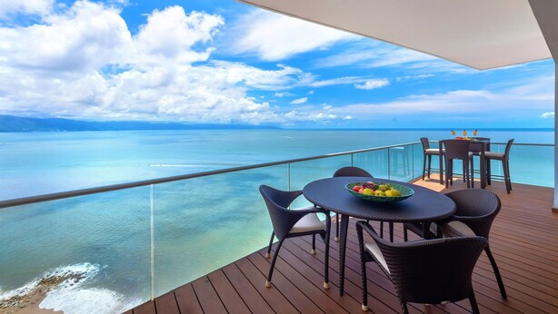 Terraza con mesa y sillas con vista al mar azul y despejado.