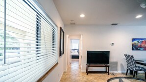A modern living room with a large TV, a patterned chair, and a glass table.