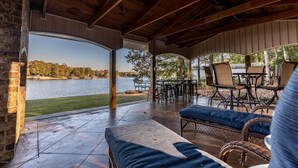 A covered patio with a view of a lake, outdoor furniture, and a brick wall. - Luxury Lakefront Getaway on Beautiful Lake Sinclair (Eatonton)