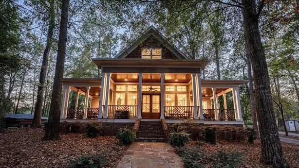 A wooden cabin with a stone pathway leading to a porch, surrounded by trees. - Luxury Lakefront Getaway on Beautiful Lake Sinclair (Eatonton)