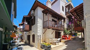 Un carrer estret amb edificis de pedra tradicionals, terrasses exteriors i un patinet aparcat.
