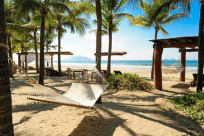 A beach with palm trees, a hammock, and wooden structures.