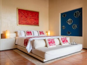 A hotel room with a bed, nightstands, and artwork on the walls.