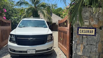 A white SUV parked in front of a gated entrance with a sign reading 'CASAMAR'.