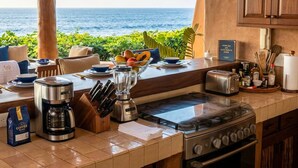 Eine Küche mit Meerblick, ausgestattet mit Kaffeemaschine, Mixer, Toaster und Herd.