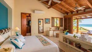 Ein Hotelzimmer mit einem Bett, einem Schreibtisch, einem Stuhl, einem Bücherregal und Blick auf den Strand.