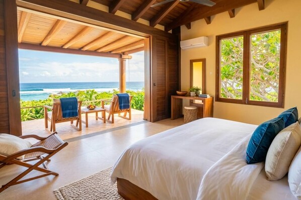 A bedroom with a large bed, a desk, and a view of the ocean. - Casamar, beach front estate on Troncones Point (La Majahua)