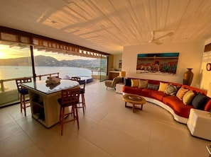 A spacious living area with a dining table, a sofa, and a view of the sea. - KauKan B7 Luxury Condo with Breathtaking View (Zihuatanejo)