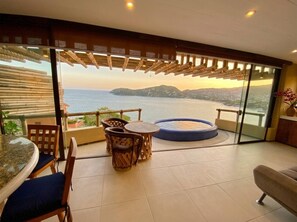 A balcony with a view of the sea, a round table with chairs, and a sofa.