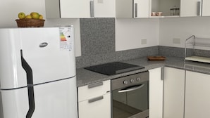 A modern kitchen with white cabinets, a built-in oven, a refrigerator, and a granite countertop. - Divino Loft - Mas Centrico Imposible (Salta)