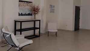 A spacious living room with a modern sofa, a small white chair, and a console table with a decorative piece above it. - Divino Loft - Mas Centrico Imposible (Salta)