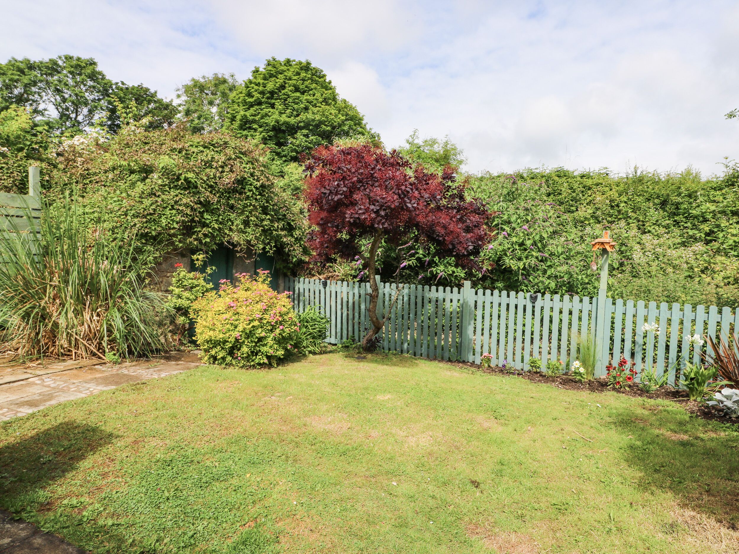 A well-maintained garden with a variety of plants and a wooden fence.