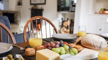 A breakfast setting with cheese, grapes, bread, and juice on a wooden table.
