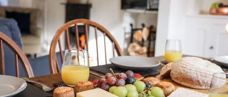 Desayuno con queso, uvas, pan y jugo sobre una mesa de madera.