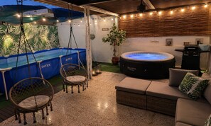 Un patio con jacuzzi, sillas colgantes y mesa de billar.