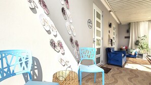 A patio area with blue chairs and tables, a wicker basket, and a wall decorated with flip-flops. - Pool - Water tank -Solar panels  5 Min AiRpOrT & Isla Verde Beach! Watch Video - (Carolina)