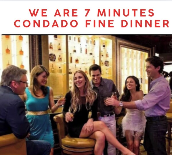 Un grupo de personas en un comedor con un letrero que dice 'WE ARE 7 MINUTES CONDADO FINE DINNER'.