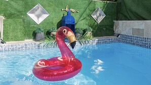 A swimming pool with a flamingo float, a blue decorative bottle, and a 'home' sign on a green wall. - Pool - Water tank -Solar panels  5 Min AiRpOrT & Isla Verde Beach! Watch Video - (Carolina)