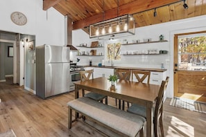 Una cucina moderna con un tavolo da pranzo in legno, elettrodomestici integrati e vista sull'esterno.